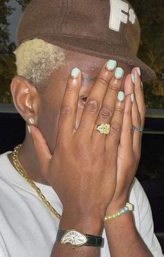 a man covering his face with both hands and wearing a brown hat on top of his head