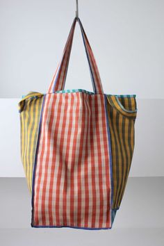 an orange and yellow striped bag hanging from a hook on a white wall with no background