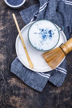 a white plate topped with a cup of milk and a wooden spoon next to it