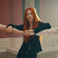 a woman with long red hair is holding another woman's hand