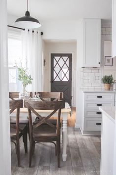 a dining room table and chairs in a kitchen with white walls, wood floors and cabinets