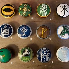 a bunch of buttons sitting on top of a wooden table with numbers and symbols painted on them