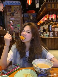 a woman sitting at a table eating food with chopsticks in front of her