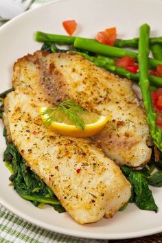 a white plate topped with fish and asparagus