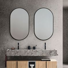 two round mirrors on the wall above a double sink