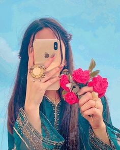 a woman taking a selfie with her cell phone and flowers in front of her