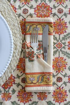 a fork and knife sitting on top of a napkin next to a plate with a flower design