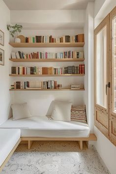 a room with bookshelves and a bed in the corner next to a window