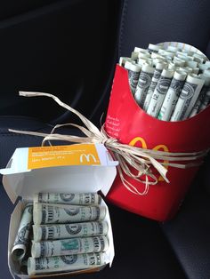 a red bucket filled with money sitting on top of a seat next to a bag