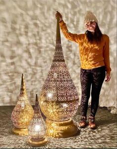 a woman standing next to three shiny vases