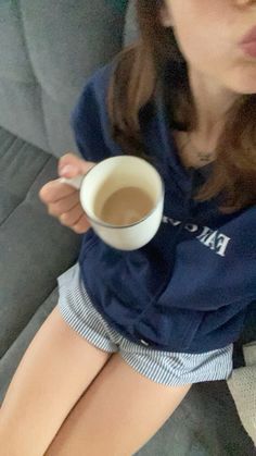 a woman sitting on a couch holding a cup of coffee