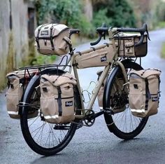 a bicycle with two bags strapped to the front and back rack, parked on a road