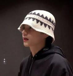 a young man wearing a white and black knitted hat while looking off to the side