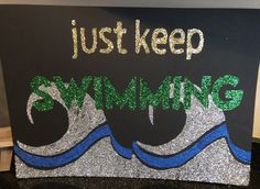 a sign that says just keep swimming on the side of a blackboard with silver and green glitters