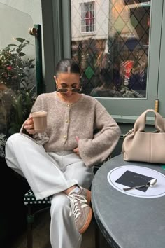 a woman sitting at a table holding a coffee cup