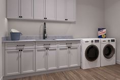 a washer and dryer in a white laundry room with cabinets on the wall