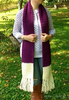 a woman standing in the grass wearing a purple and white scarf