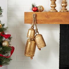 two bells hanging from a mantle next to a christmas tree