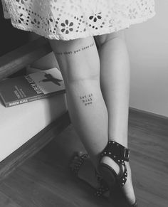 a woman's legs with tattoos on them and a book in front of her