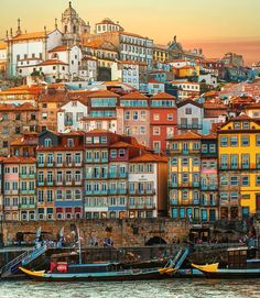 several boats are parked in front of some buildings on the water and one is yellow