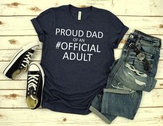 a t - shirt that says proud dad of an official adult with ripped jeans and sneakers