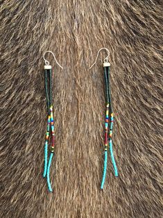 two pairs of earrings with beads on them sitting on top of a fur covered surface