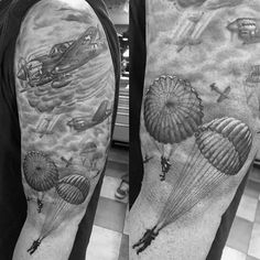 a man's arm with two parachutes and an airplane in the sky on it