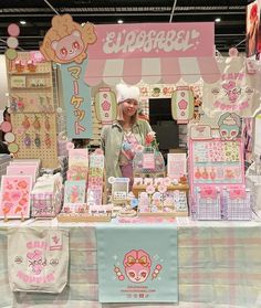 a woman standing in front of a table filled with cards and paper goods for sale