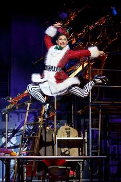 a man dressed as santa clause riding on top of a metal structure with his arms in the air