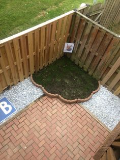 a wooden fence with grass growing in the middle and gravel on the ground next to it