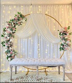 a white bench sitting in front of a wall covered in flowers and greenery with lights behind it