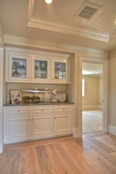 an empty kitchen with white cabinets and wood flooring in the middle of the room