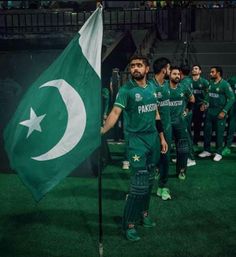 pakistan's cricket team walk out onto the field with their national flag in hand