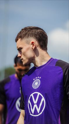 two soccer players in purple uniforms standing next to each other