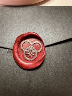 a close up of a red wax seal on a gray envelope with an olympic symbol in the center