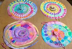 three paper plates with different designs on them sitting on top of a wooden table next to scissors and thread