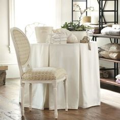 a dining room table and chairs with white linens on the top, in front of a window