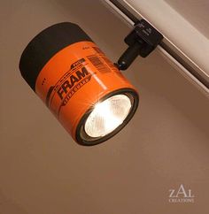 an orange light is hanging from the ceiling in front of a white wall with text reading oil filter track light / track head