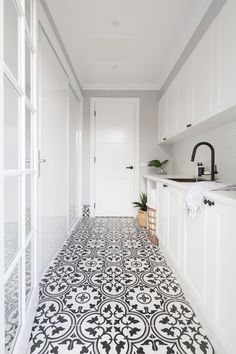 a white and black tile floor in a bathroom next to an open door with potted plants on the window sill