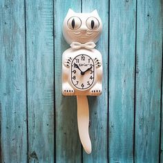 a clock with a cat face on the side of a wooden wall next to a fence