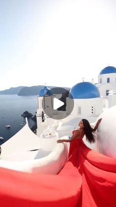 a woman in a red dress standing on the edge of a white building with blue domes