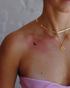 a woman wearing a necklace with a sun and moon tattoo on her left side chest