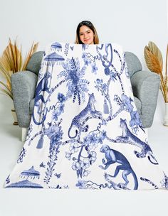 a woman sitting on a couch under a blue and white blanket with an animal print