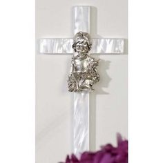 a cross with a teddy bear on it and purple flowers in the foreground, against a white background