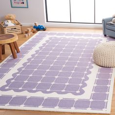 a purple and white rug in a living room next to a blue couch with a teddy bear on it