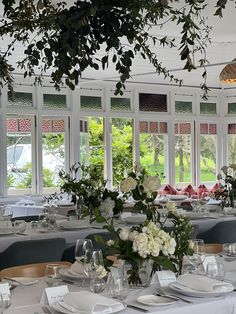 a dining room with tables and chairs set up for an event or function in front of large windows