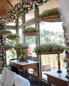 flowers and greenery are arranged in baskets on the window sill above a couch