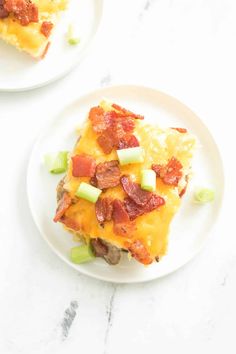 two white plates topped with breakfast casserole covered in bacon