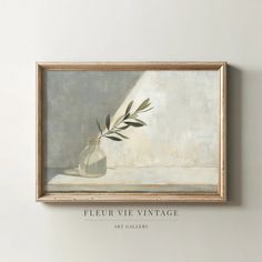 a painting hanging on the wall above a vase with an olive branch in it's center