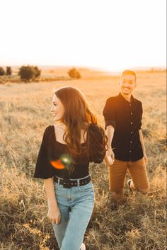 a man and woman walking through a field with the sun shining down on their faces